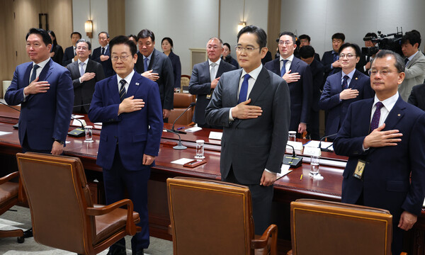  이재명 대통령이 16일 용산 대통령실에서 열린 한미 관세협상 후속 민관 합동회의에서 국기에 경례하고 있다. 앞줄 오른쪽부터 여승주 한화그룹 부회장, 이재용 삼성전자 회장, 이 대통령, 최태원 SK그룹 회장. 뒷줄 오른쪽부터 김정관 산업통상부 장관, 구광모 LG그룹 회장, 정의선 현대차그룹 회장, 서정진 셀트리온 회장, 김용범 정책실장. [연합뉴스]